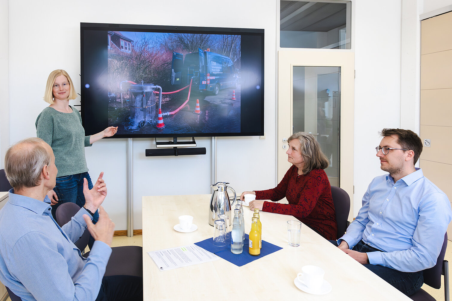 Drei Personen am Konferenztisch eine Perso zeigt ein Spülungsbild auf dem Monitor