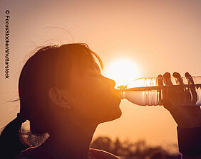 Frau trinkt aus Wasserflasche vor Sonne