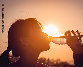 Woman with waterbottle in front of sun